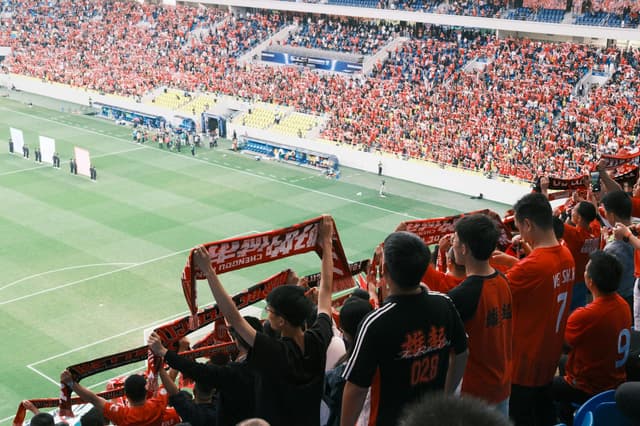 Supporters raising scarves and cheering in a stadium
